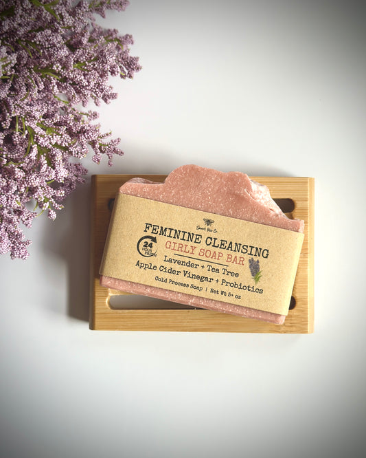 Feminine cleansing soap bar on a wooden tray with lavender flowers on a light background
