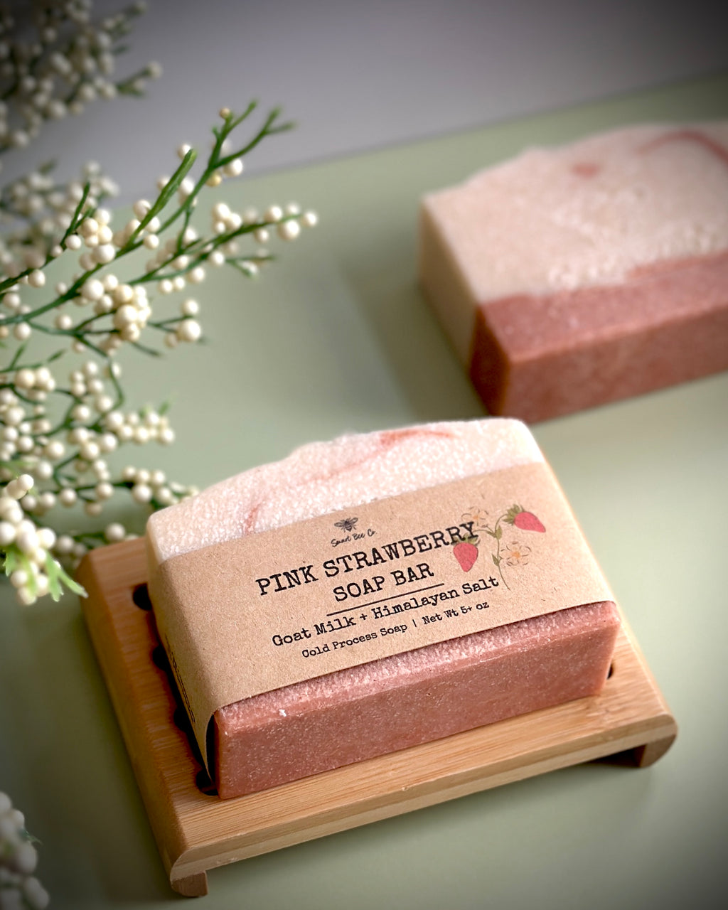 Pink strawberry soap bar on a wooden stand with a natural background