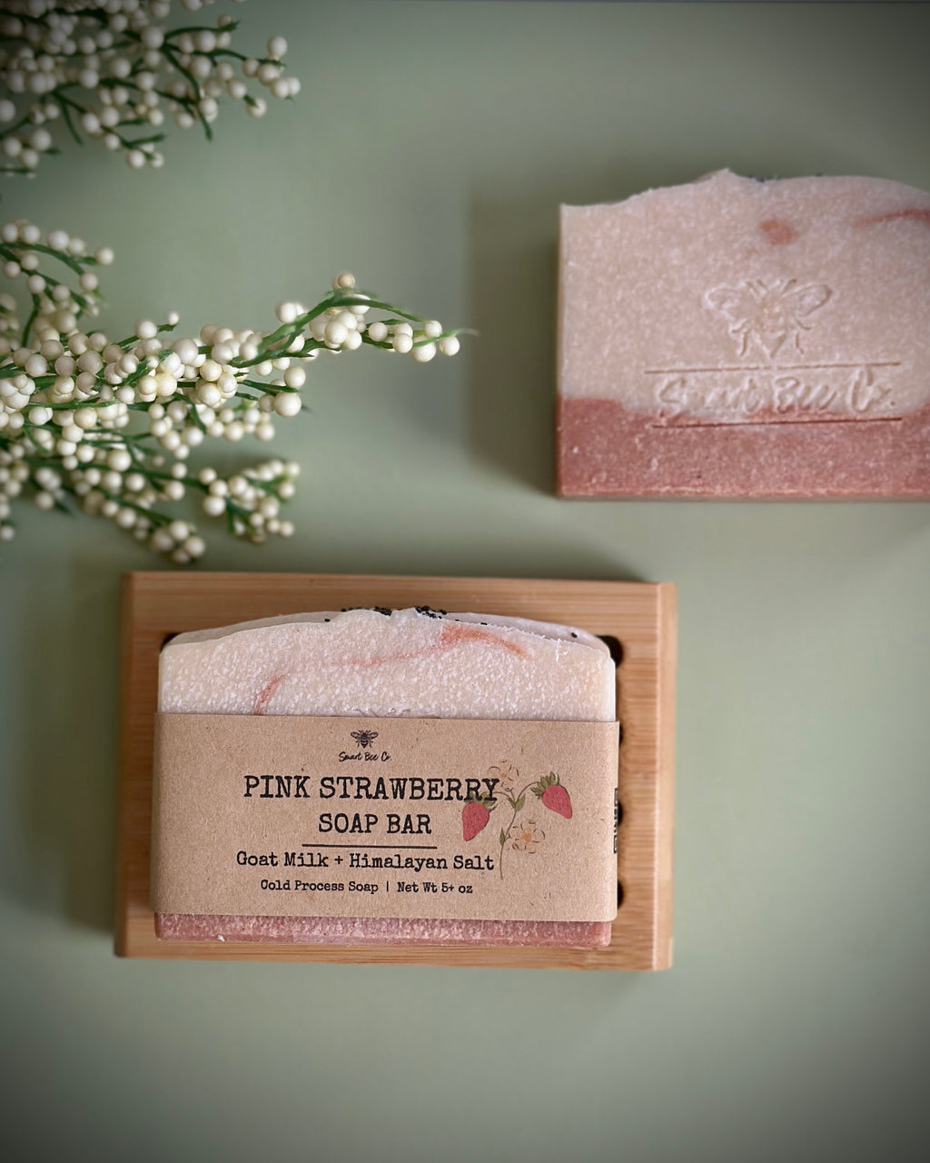 Pink strawberry soap bar in a wooden box with a green background