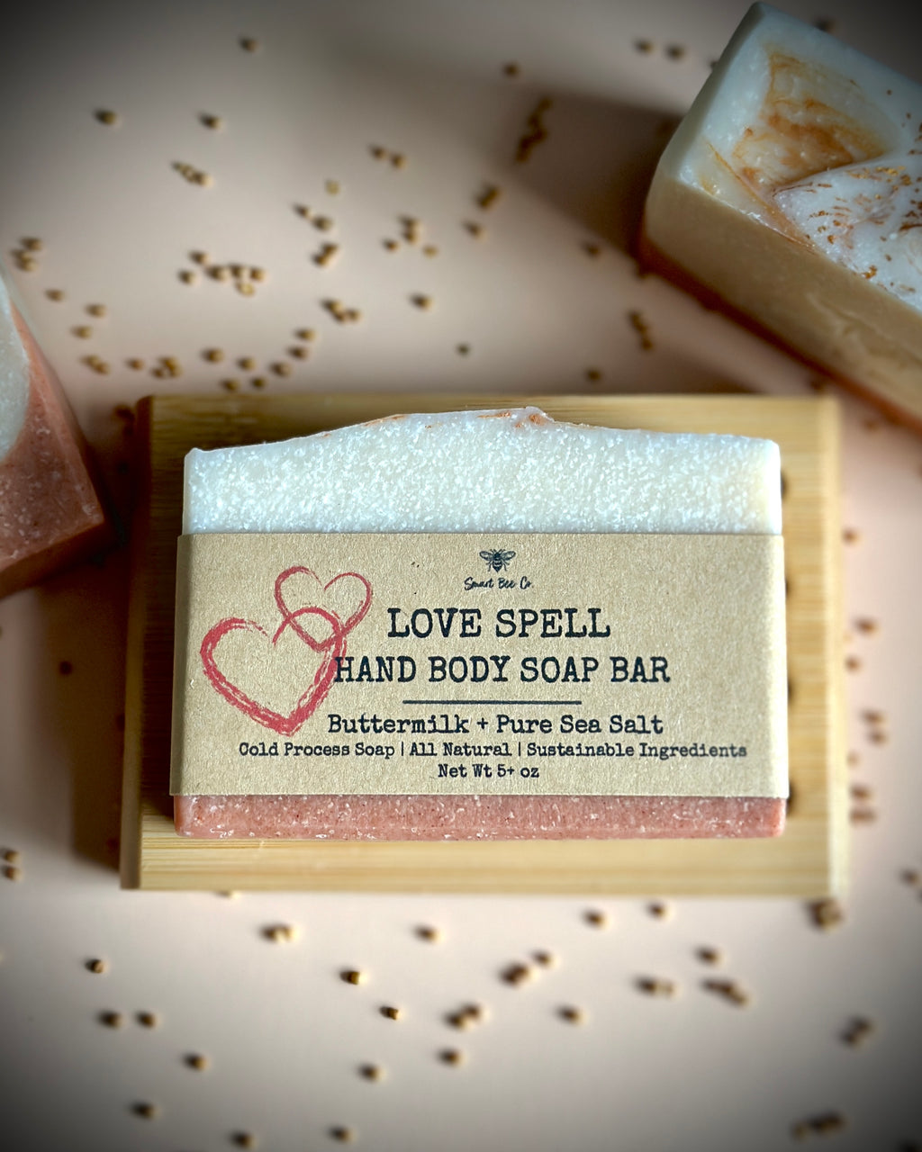 Hand body soap bar with 'Love Spell' label on a wooden block, surrounded by small decorative items.