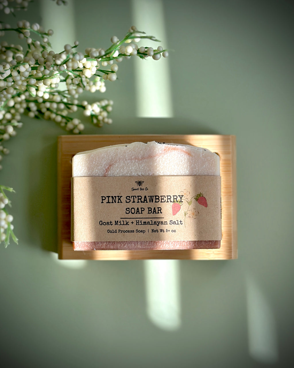 Pink strawberry soap bar on a wooden block with a natural background