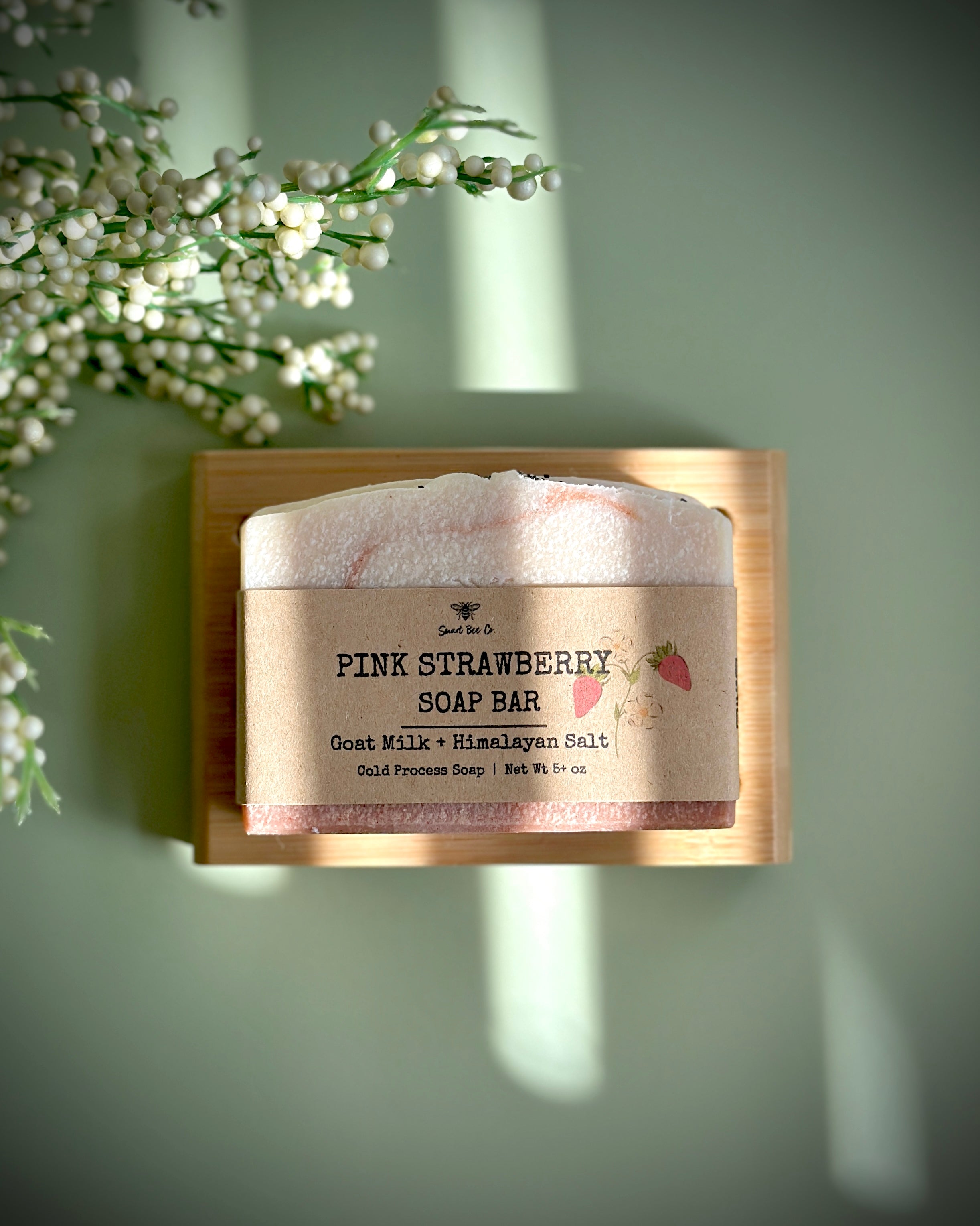 Pink strawberry soap bar on a wooden block with a natural background