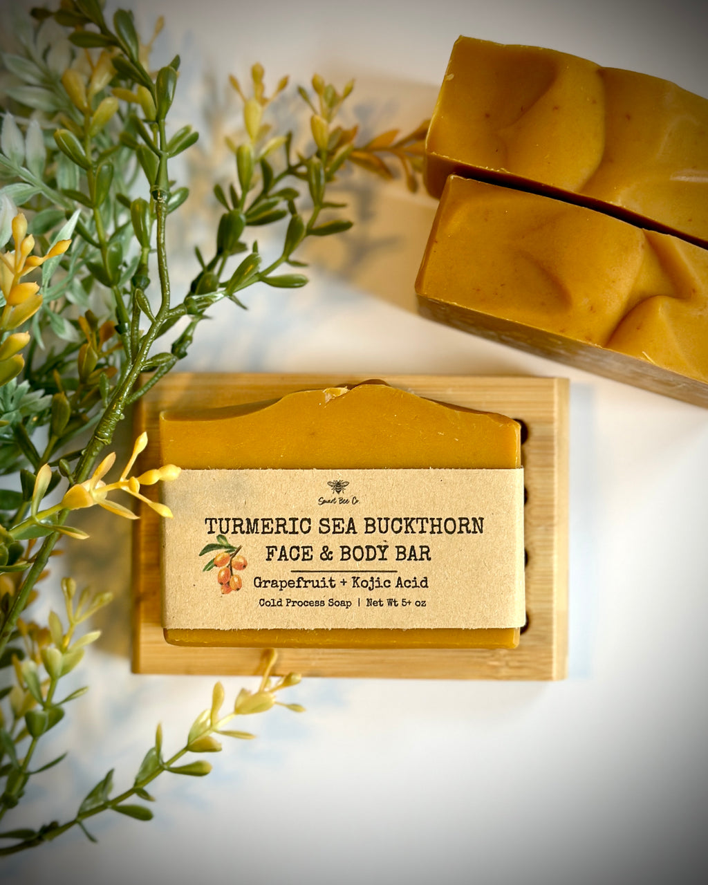 Turmeric sea buckthorn face and body bar soap on a wooden block with greenery in the background
