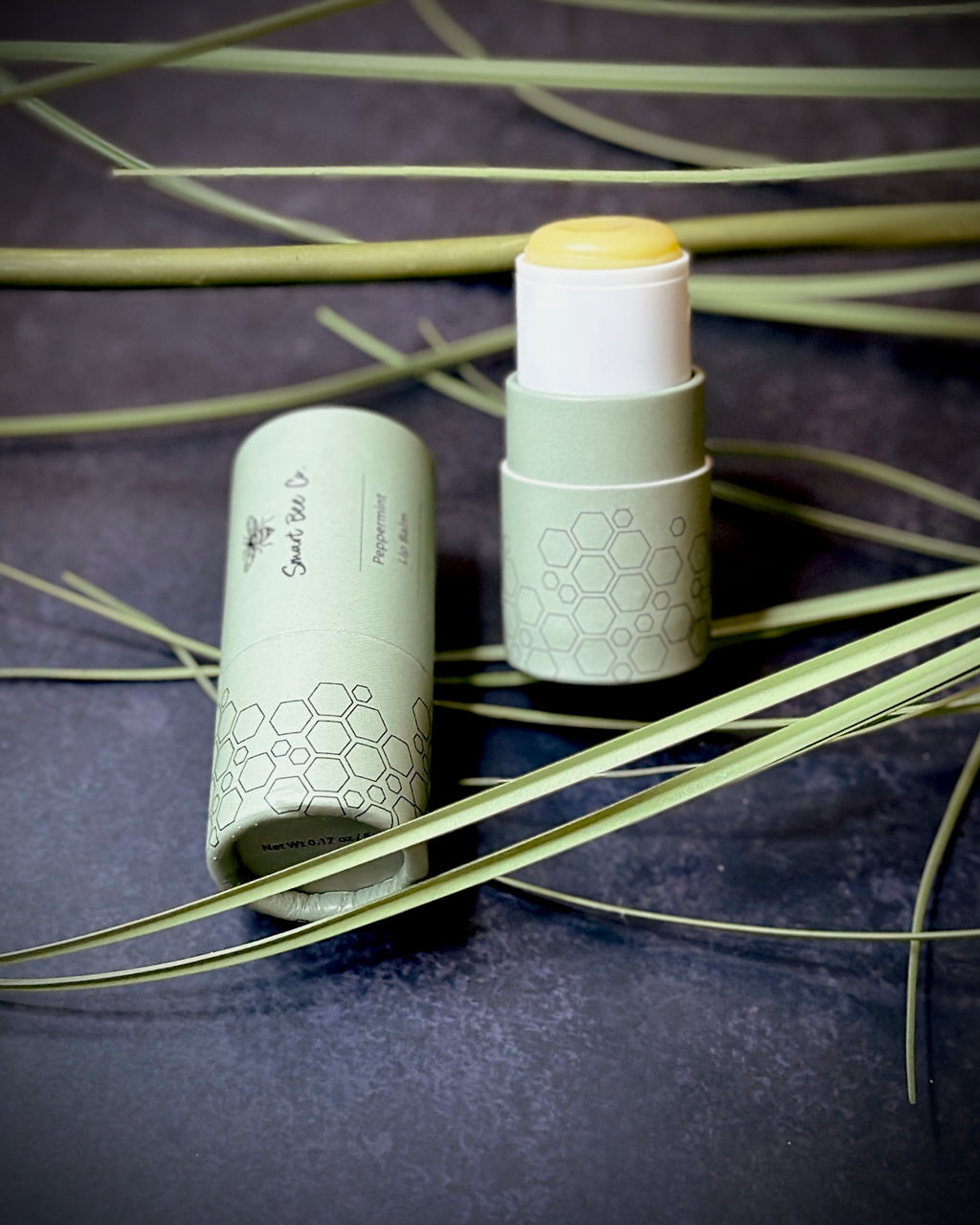 Two skincare products with honeycomb design on a dark background with leaves